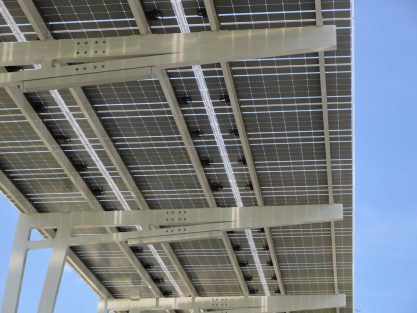 Solar panels installed over parking lot canopy shade for parked cars for effective generation of clean energy.